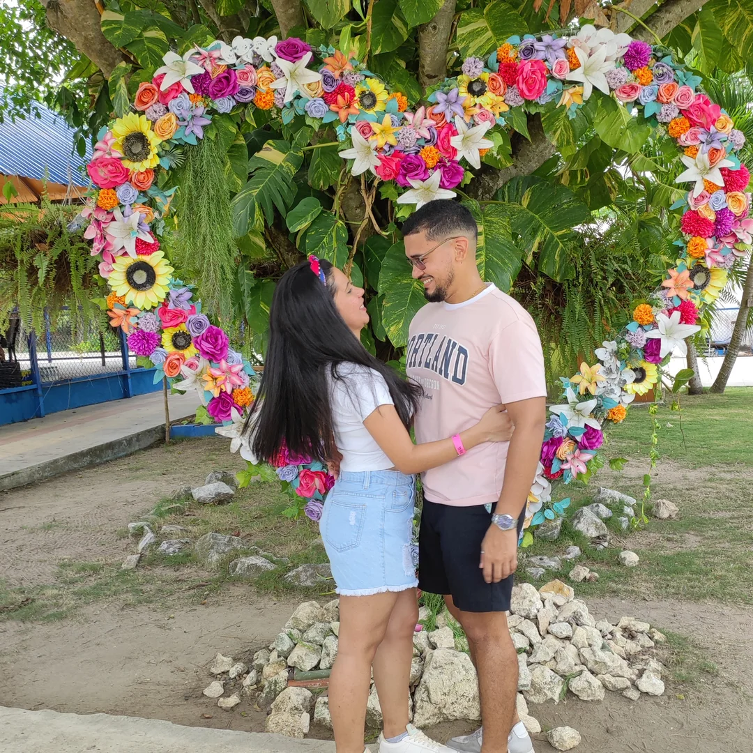 Eric y Lulys frente a un corazón de flores.